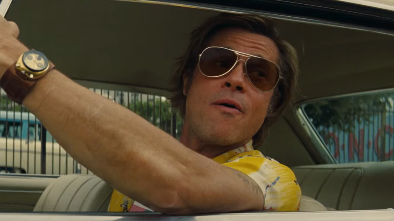 Brad Pitt looks to the side amused while in the drivers seat in Once Upon A Time In Hollywood.