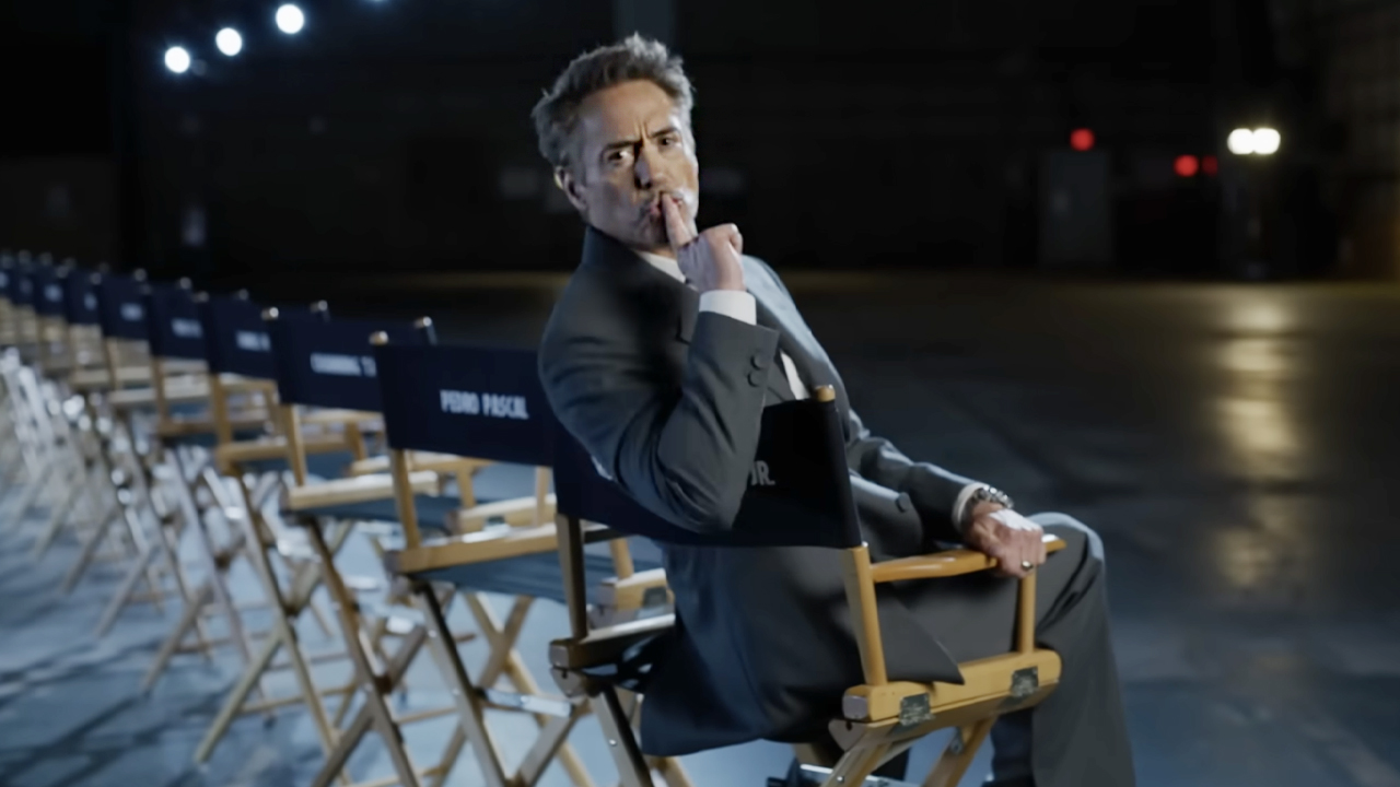 In a director&#039;s chair, a grey-suited Robert Downey Jr. shushes the camera as Marvel reveals the Doomsday cast. 