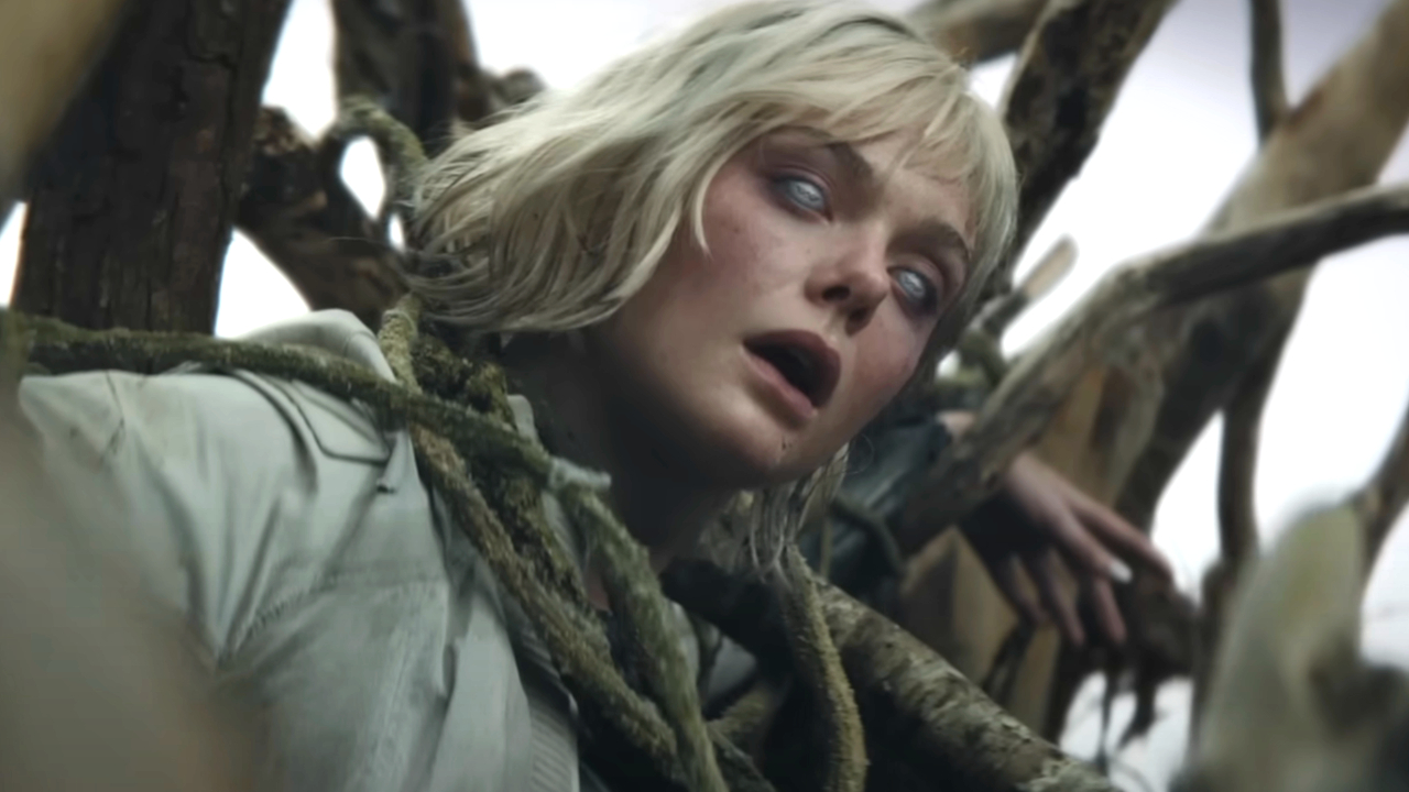 Elle Fanning stands in the middle of a cornfield with Weyland-Yutani branding showing on her eyes in Predator: Badlands. 