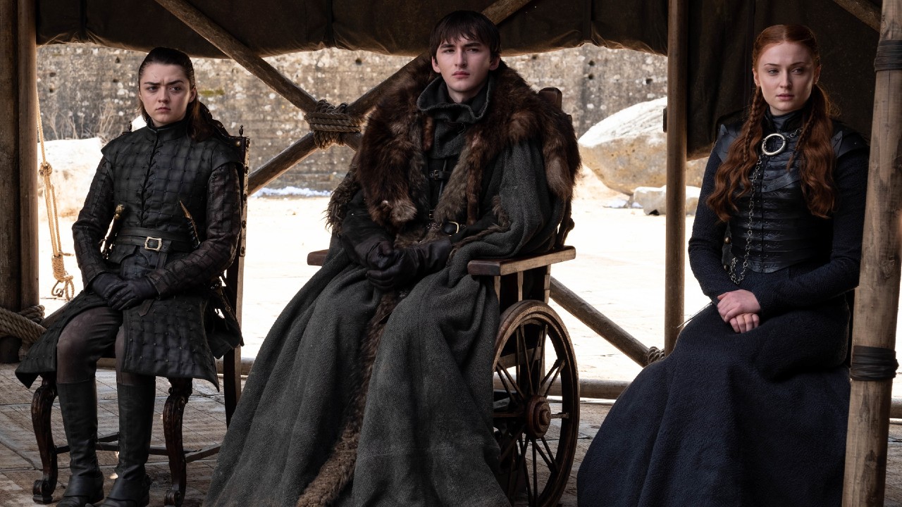 From left to right: Arya, Bran and Sansa sitting next to each other in Game of Thrones. 