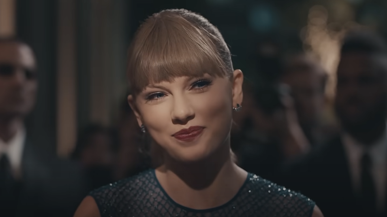 Taylor Swift politely smiles as she talks to paparazzi in the &quot;Delicate&quot; music video.